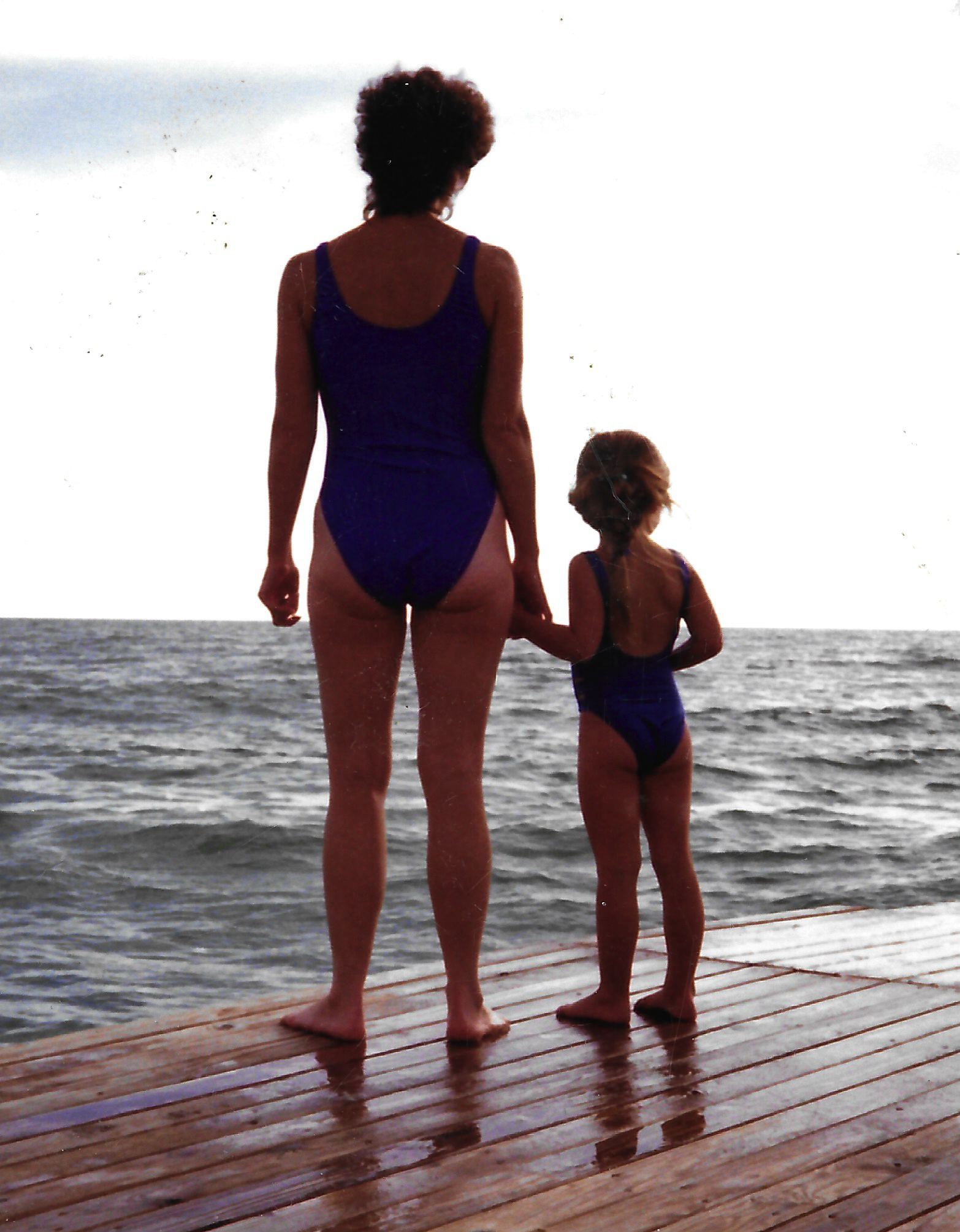 Mother and daughter holding hands on a dock overlooking the water